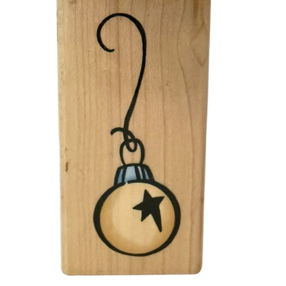 Wooden block with a black line drawing of a Christmas ornament on a white background
