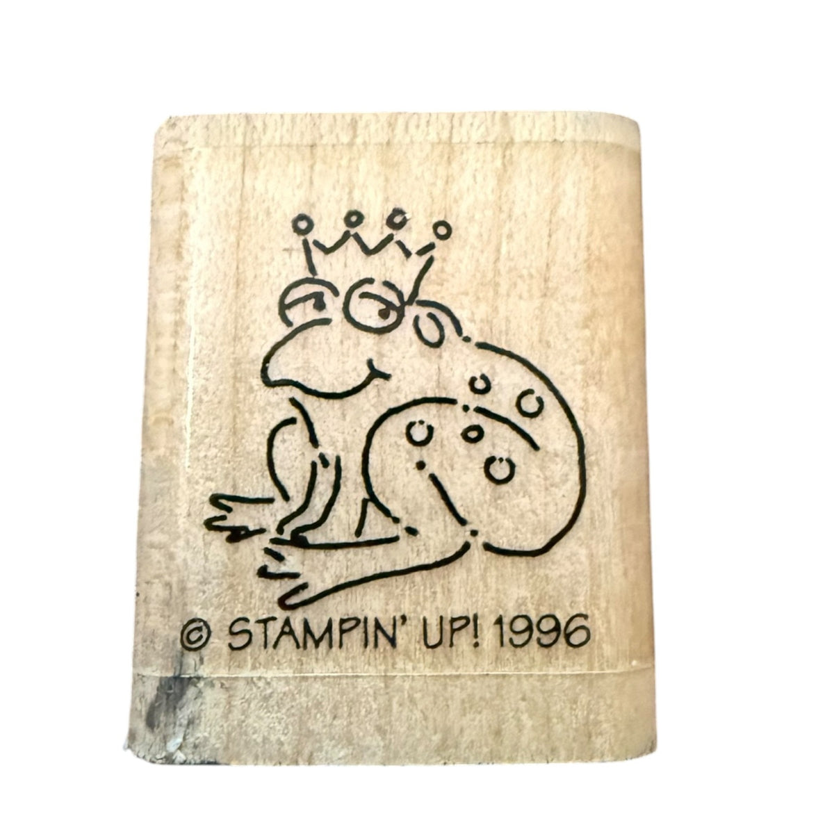 A wooden rubber stamp with a black line-art design of a cartoon frog wearing a crown, with the text '© STAMPIN' UP! 1996' printed on the bottom, shown against a plain white background.