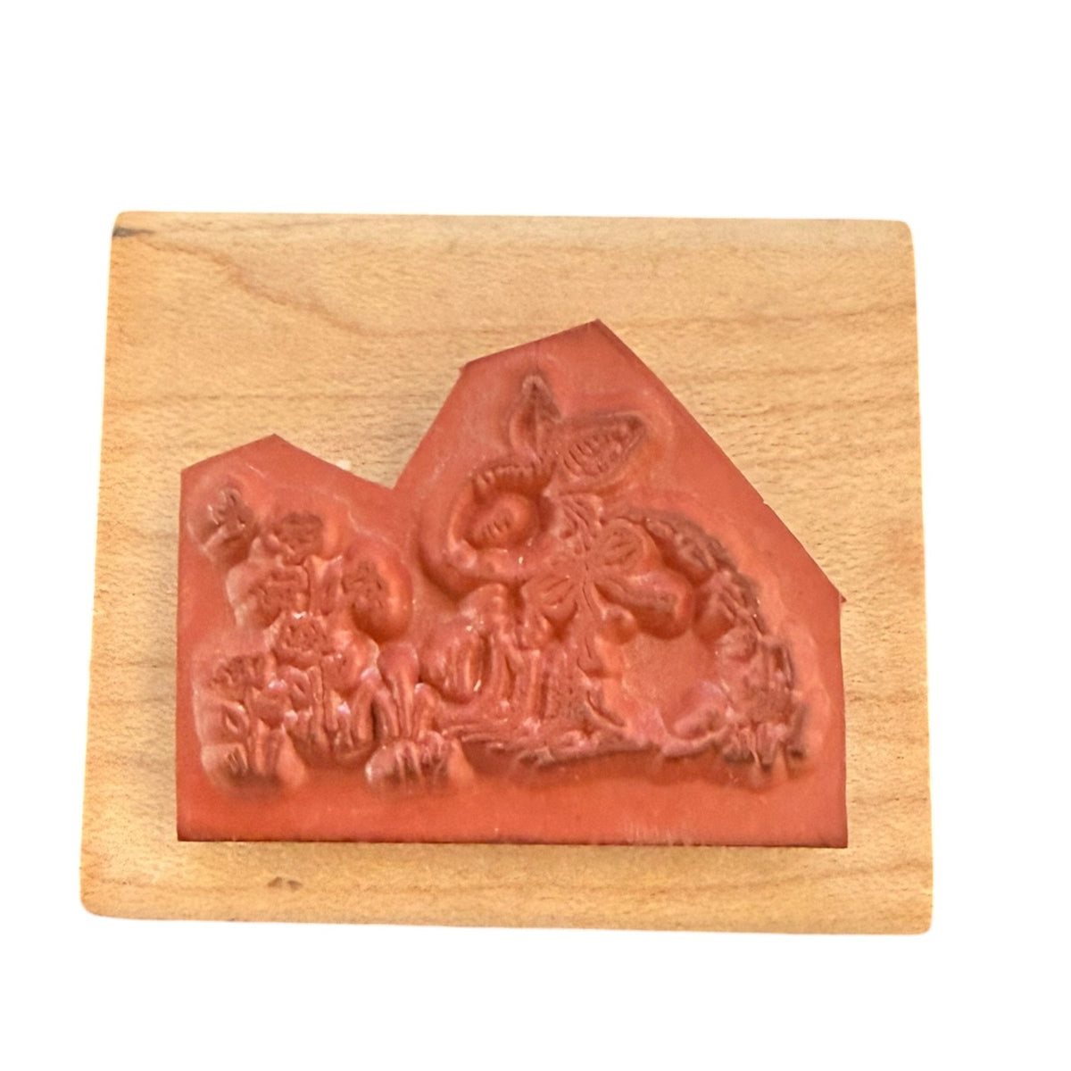 A stamp with a reddish-brown carved rubber mounted on a light-colored wooden block, shown against a plain white background.