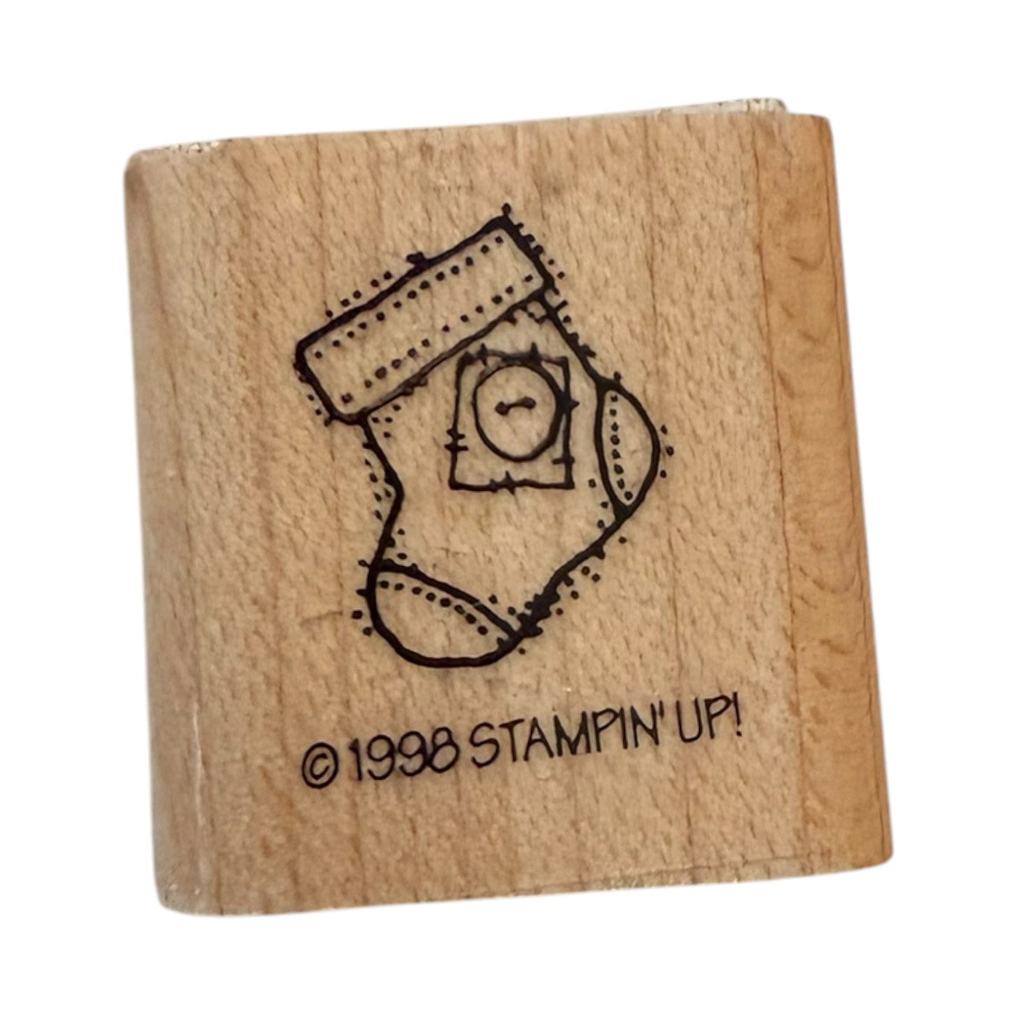 A wooden rubber stamp with a black  design of a Christmas stocking containing a small button, and the text '© 1998 STAMPIN' UP!' on the front, shown on a plain white background.