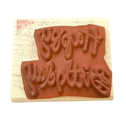 A wooden rubber stamp block with a terracotta-colored stamp face featuring the cursive text shown on a plain white background.