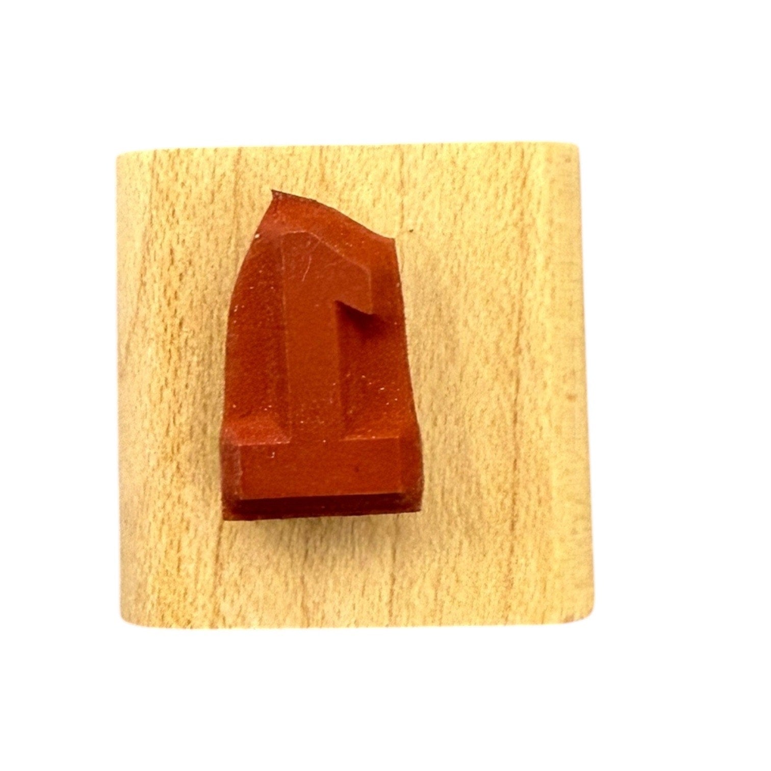 Red letter '1' stamp on a wooden block with a white background