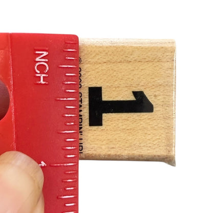 Red ruler with inch markings next to a wooden block with the number 1 on a white background .9"
