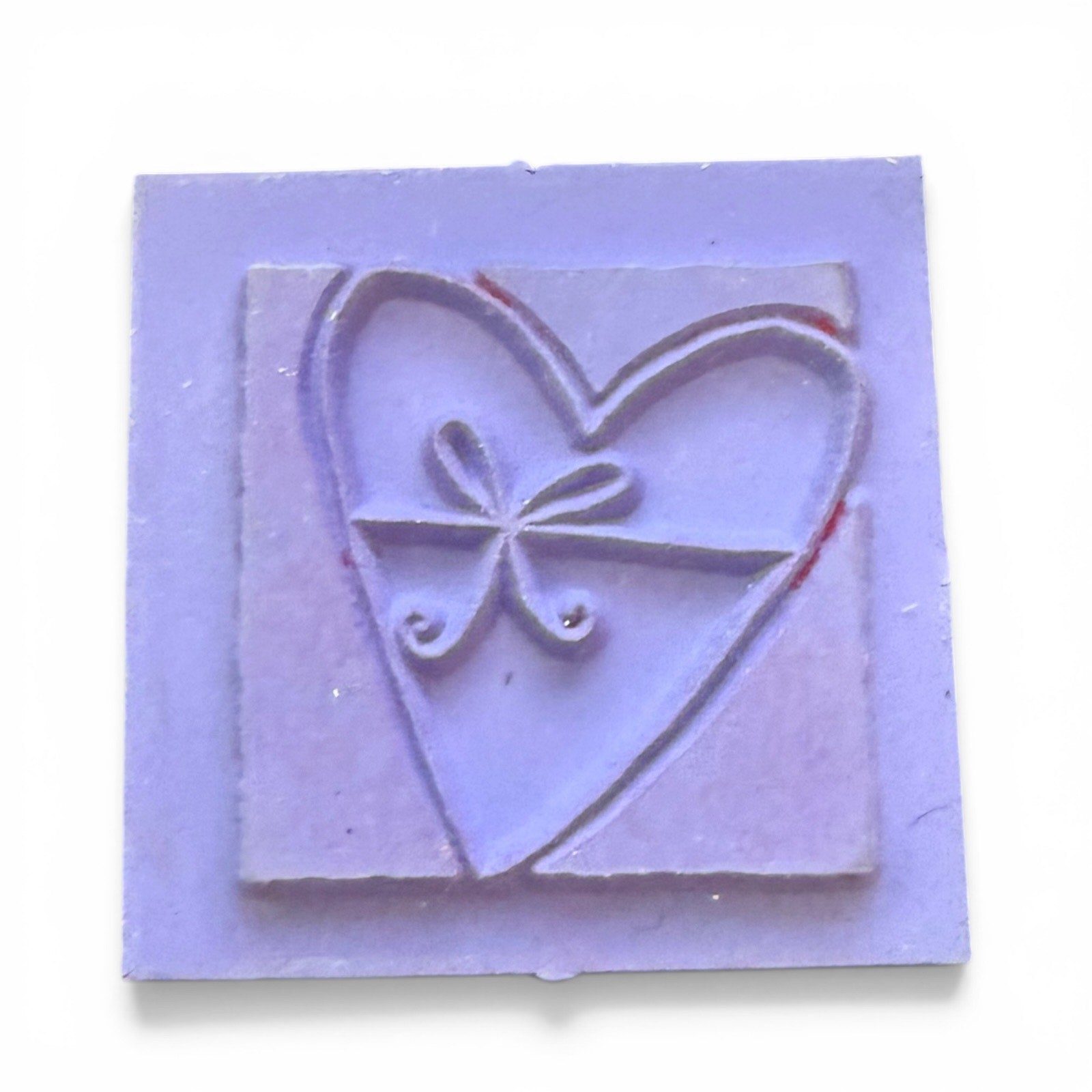 Purple rubber stamp with heart and bow design on a white background