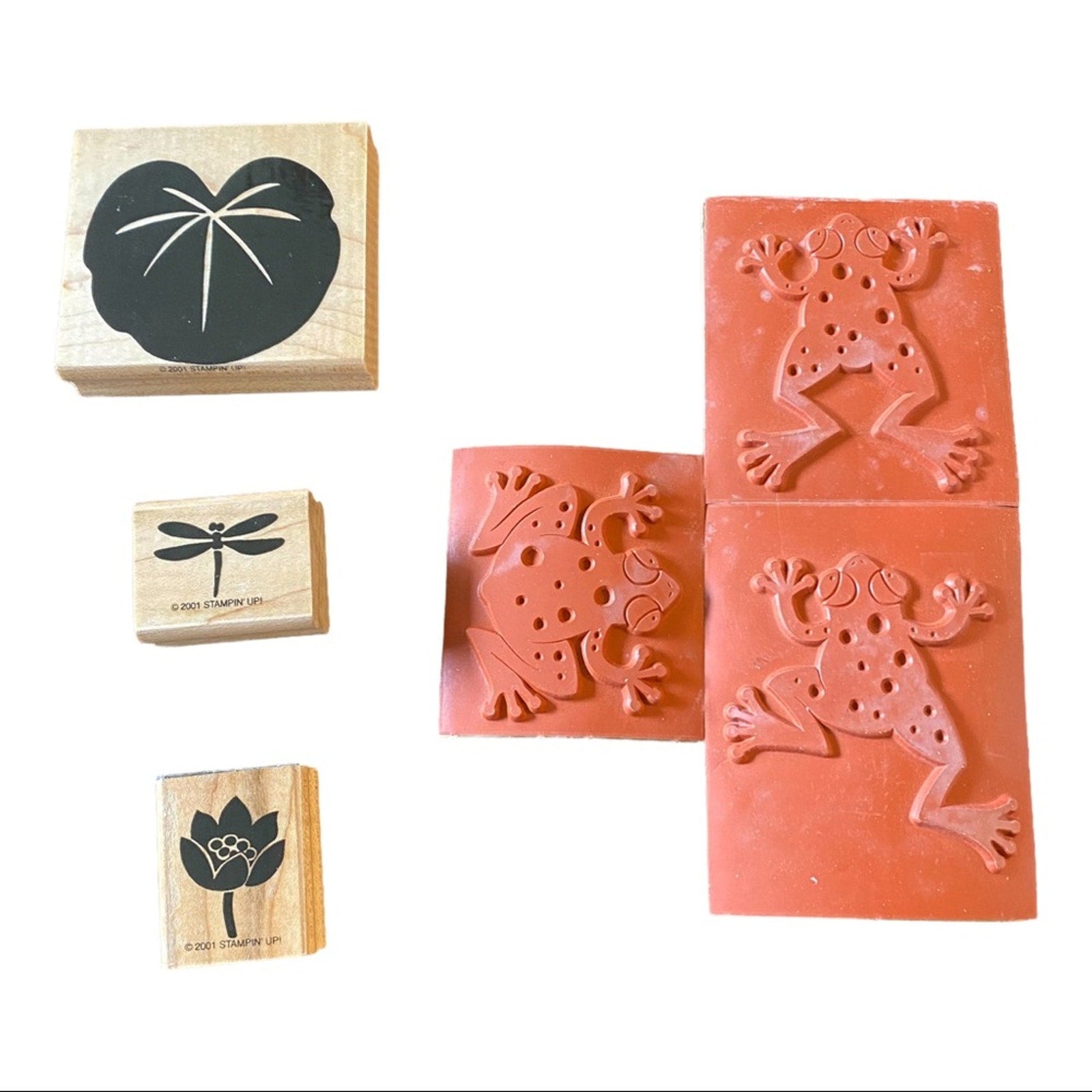 A set of rubber stamps featuring nature-themed designs, including a black lotus, dragonfly, and frog motifs, shown on a plain white background.