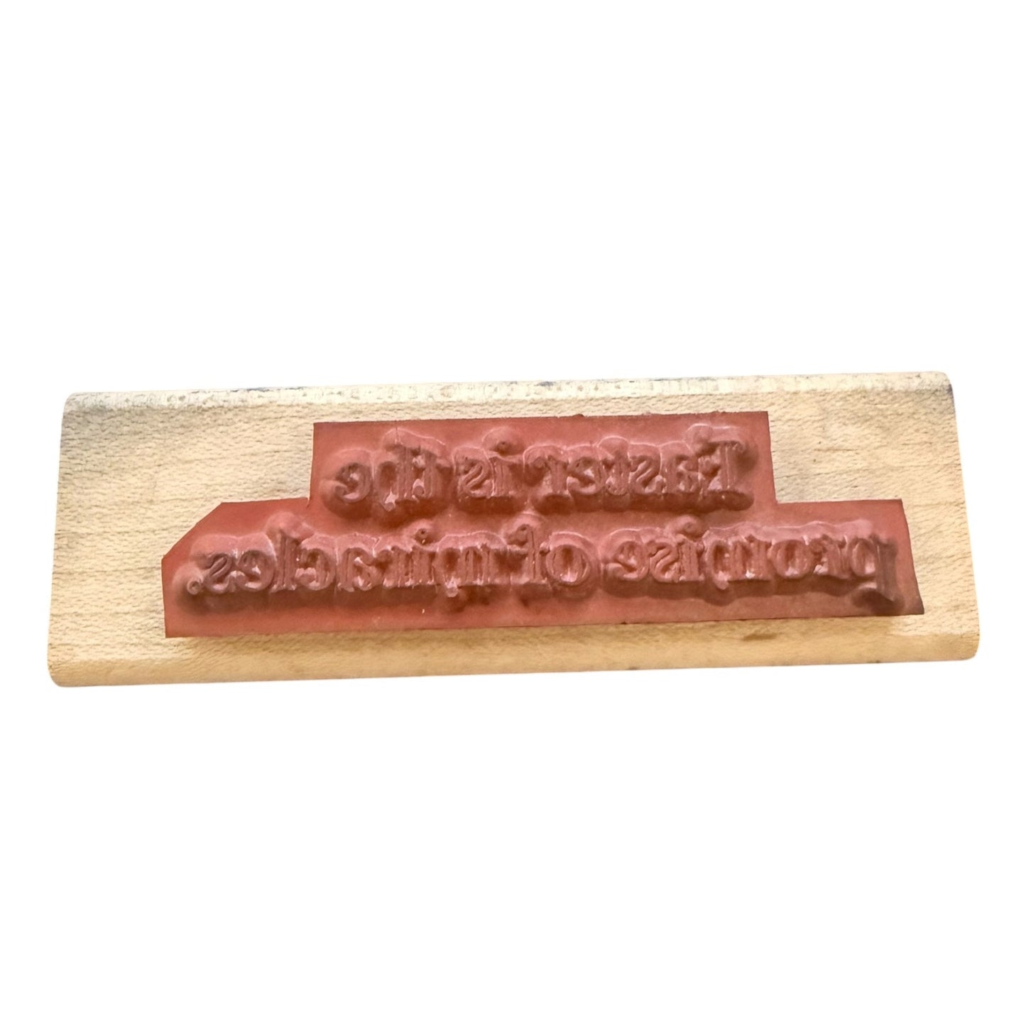 A wooden stamp block with a reddish-brown rubber stamp, on a white background.
