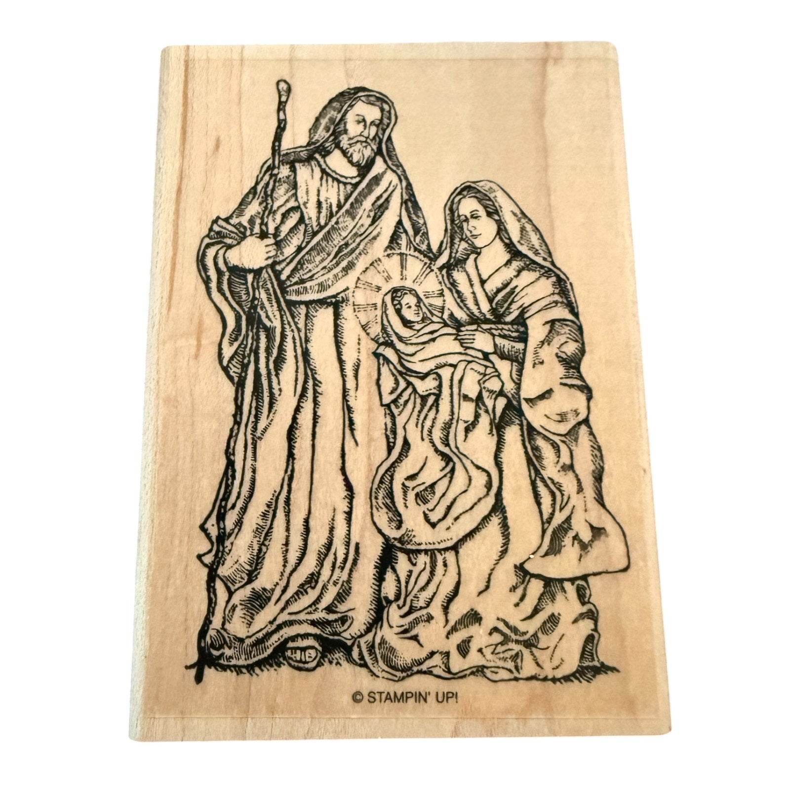 Wooden stamp with a religious scene of a man, woman, and child on a white background