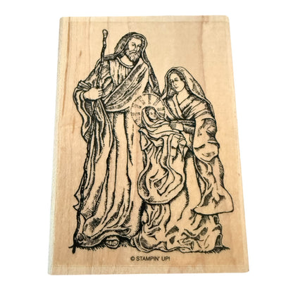 Wooden stamp with a religious scene of a man, woman, and child on a white background