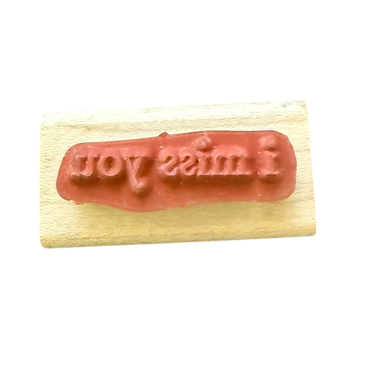 A rubber stamp on a  wood block, displaying the embossed text 'I miss you' in reverse against a plain white background.