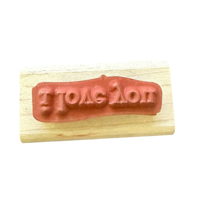 A wooden rubber stamp featuring  reddish rubber, set against a plain white background.