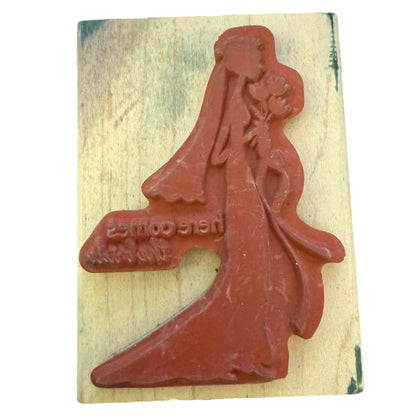 Wooden stamp with a red rubber stamp of a woman in a long dress on a wooden block.