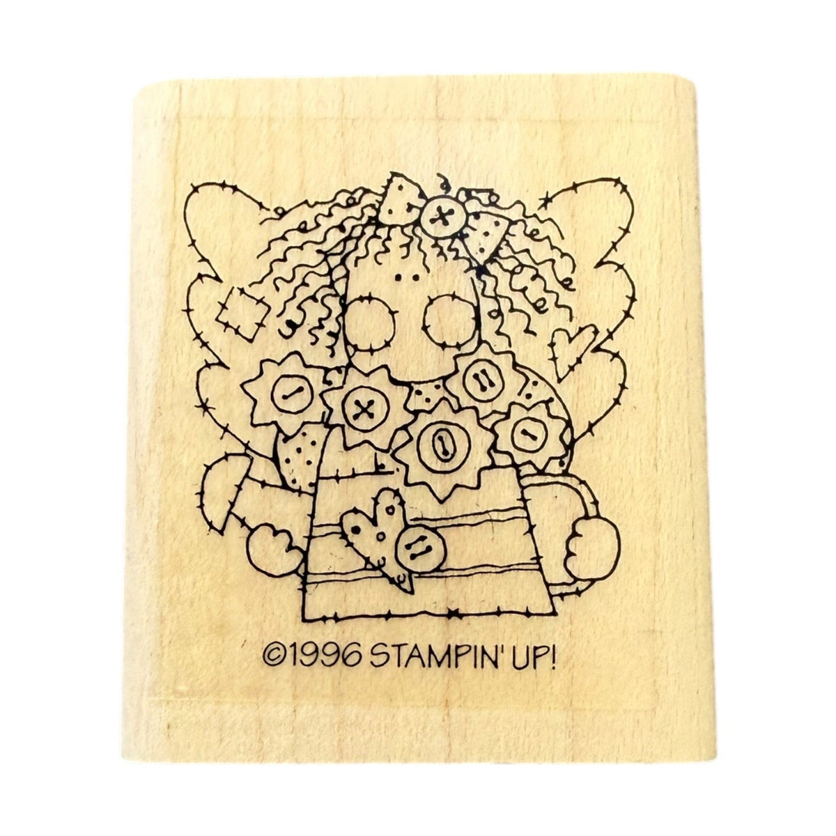 A rectangular wooden stamp block featuring a black line-art illustration of a stitched rag doll with flowers and the text '©1996 STAMPIN' UP!' on a plain white background.