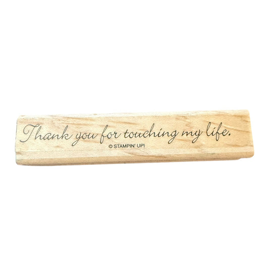 Wooden stamp with 'Thank you for touching my life' text on a white background