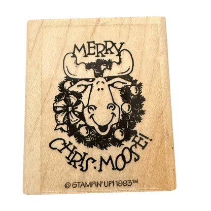 A square wooden rubber stamp featuring a design of a smiling Christmas moose wearing a wreath, with the text 'MERRY CHRIS MOOSE' and a copyright mark for Stampin' Up! 1993.