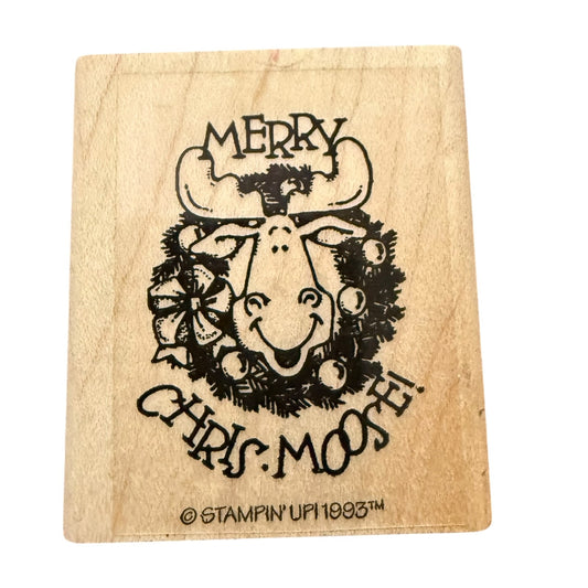 A square wooden rubber stamp featuring a design of a smiling Christmas moose wearing a wreath, with the text 'MERRY CHRIS MOOSE' and a copyright mark for Stampin' Up! 1993.