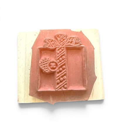 Decorative rubber stamp with a present design on a wooden block against a white background
