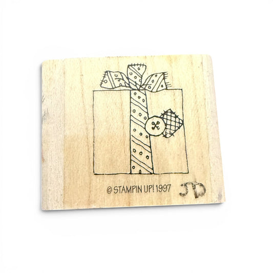 Wooden stamp with a design of a gift box and ribbons on a white background