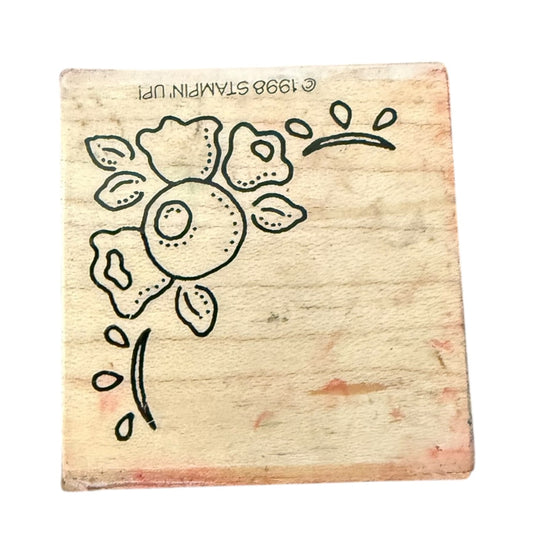 A square wooden rubber stamp block with a black line-art floral design, photographed on a plain white background. The stamp shows the stamped text '© 1998 STAMPIN' UP!' on the wood.