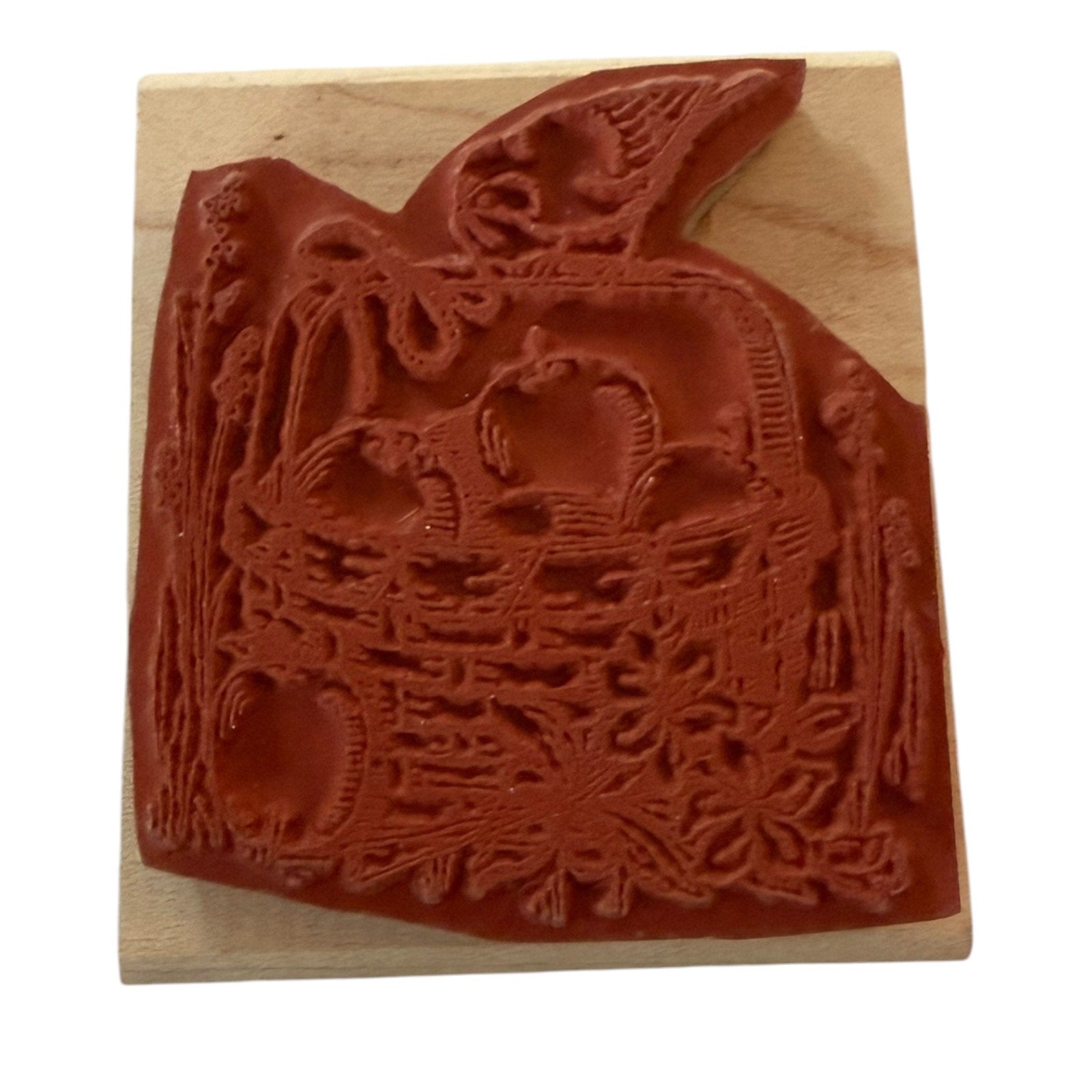A wooden rubber stamp featuring an embossed autumn harvest design with apple, a basket, and a bird, shown on a light wood block against a white background.