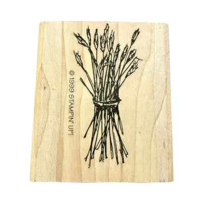 A rectangular wooden stamp block with a black line drawing of a tied bundle of wheat , shown on a plain white background.