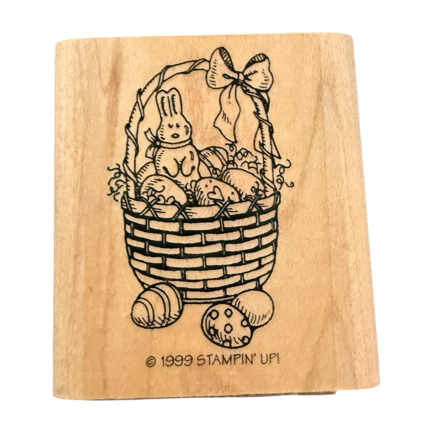 A wooden stamp block with an Easter basket design featuring a bunny, eggs, and decorative bow, with the text '© 1999 STAMPIN' UP!' at the bottom, shown on a plain white background.