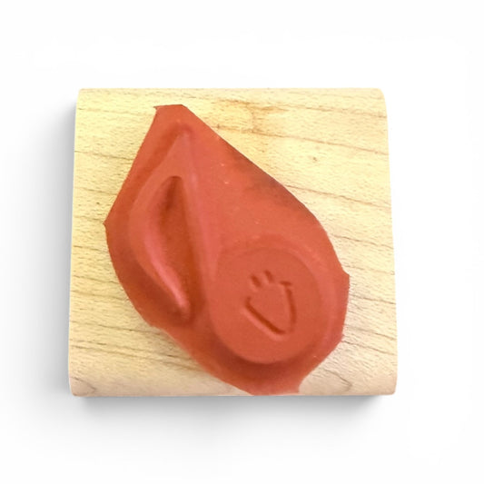 Red rubber stamp on a wooden block with a white background