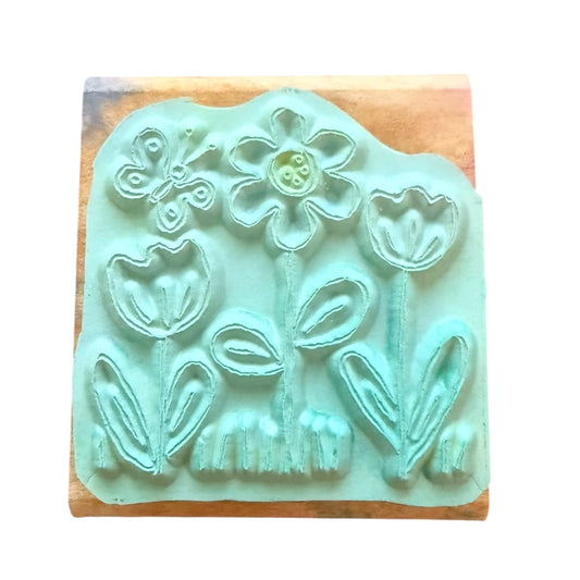 Teal floral stamp on a wooden block with a white background