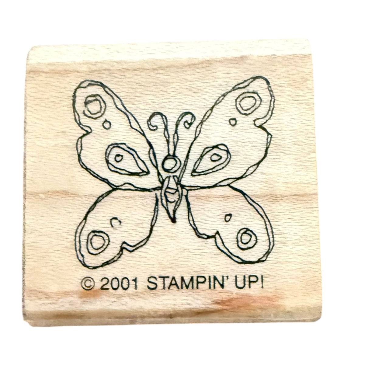 A wooden rubber stamp block featuring a butterfly design and the text '© 2001 STAMPIN' UPI' on a plain white background.