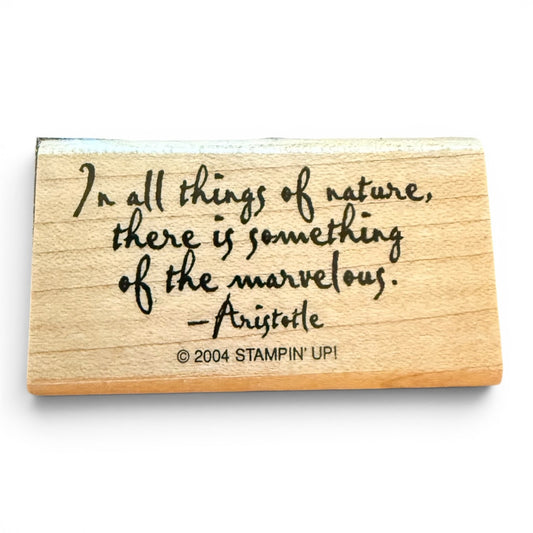 Wooden stamp with engraved quote by Aristotle on a white background