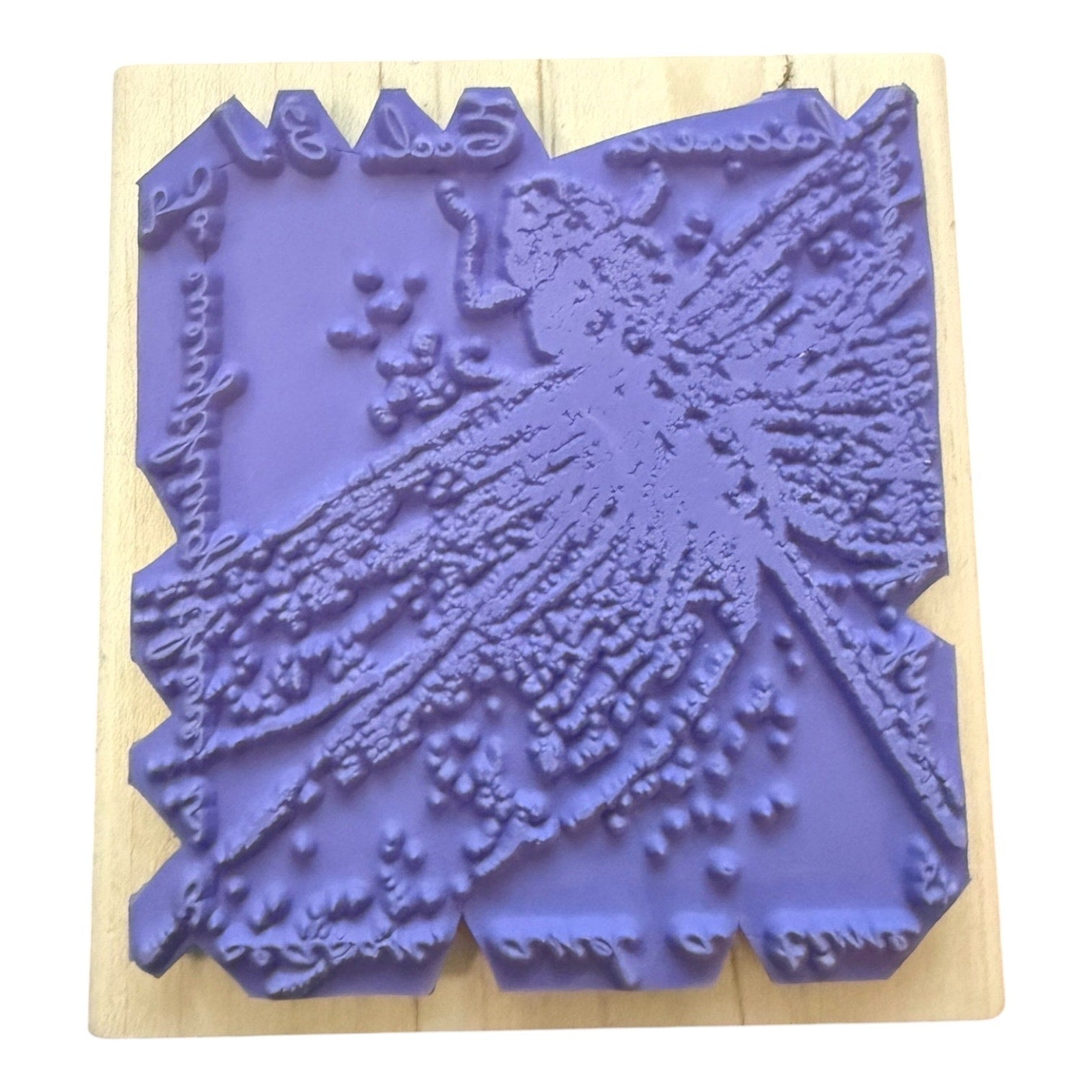 A purple rubber stamp with an embossed dragonfly design, mounted on a light-colored wooden block against a white background.
