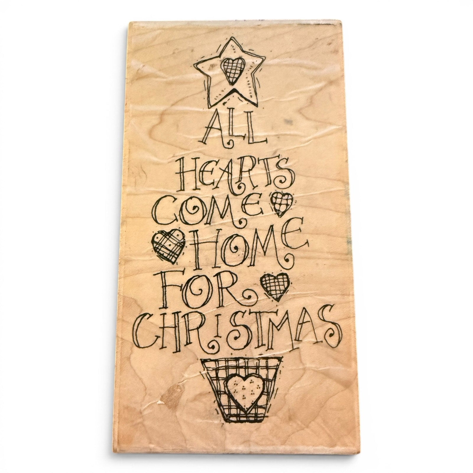 Wooden stamp with Christmas-themed text and heart designs on a white background