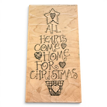 Wooden stamp with Christmas-themed text and heart designs on a white background