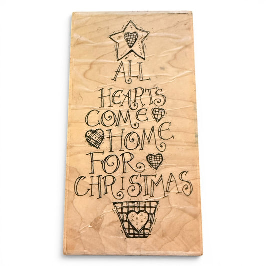 Wooden stamp with Christmas-themed text and heart designs on a white background