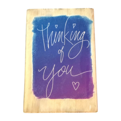 Wooden board with 'Thinking of You' text in white on a blue and purple gradient background