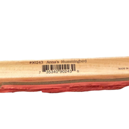 A close-up of a wooden rubber stamp block showing printed text that reads '#90243 Anna's Hummingbird' above a barcode.