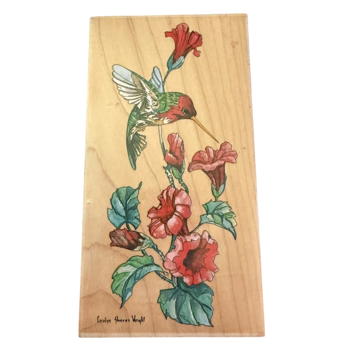 A rectangular wooden block stamp featuring a illustration of a green hummingbird and red flowers with green leaves, shown against a plain white background.