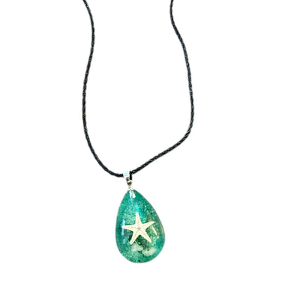 Teal pendant with a starfish on a black cord against a white background