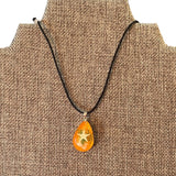 Necklace with an orange pendant featuring a starfish design on a brown textured background
