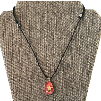 Necklace with a red teardrop pendant featuring a star on a brown textured background