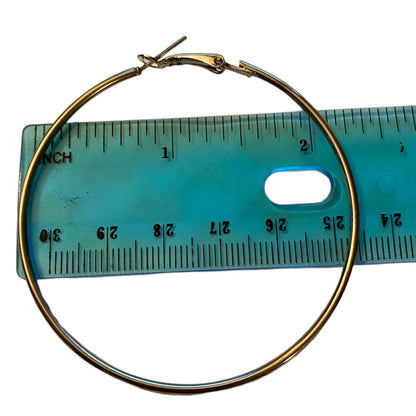 A silver hoop earring with a spring clasp, shown next to a translucent blue ruler for scale on a white background.