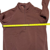 Pink fleece pullover with a measuring tape draped over it on a white background