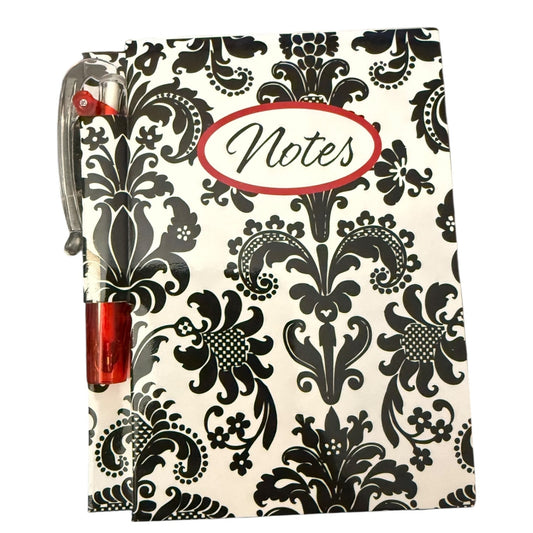 Notebook with black floral pattern and red pen on a white background