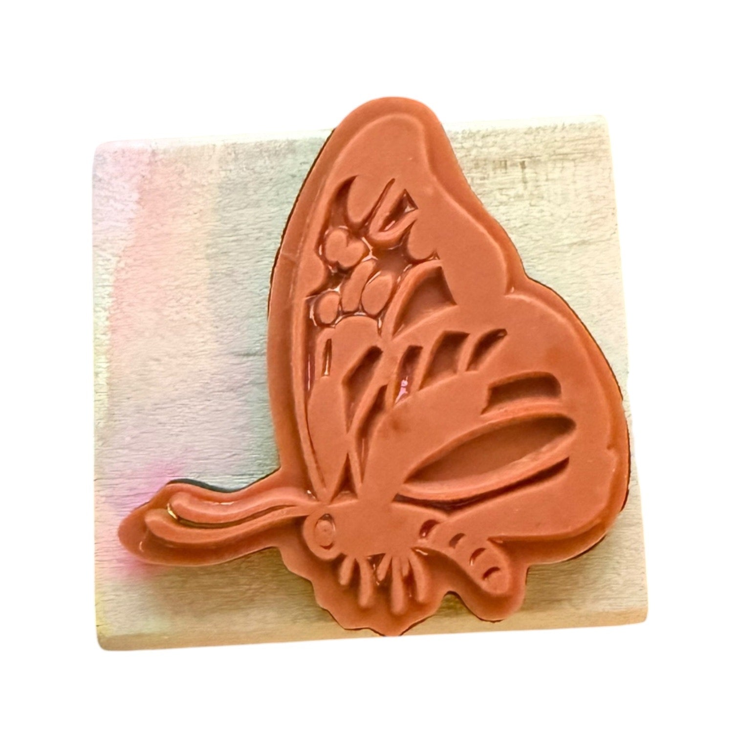 Butterfly-shaped stamp on a wooden block with a colorful striped background