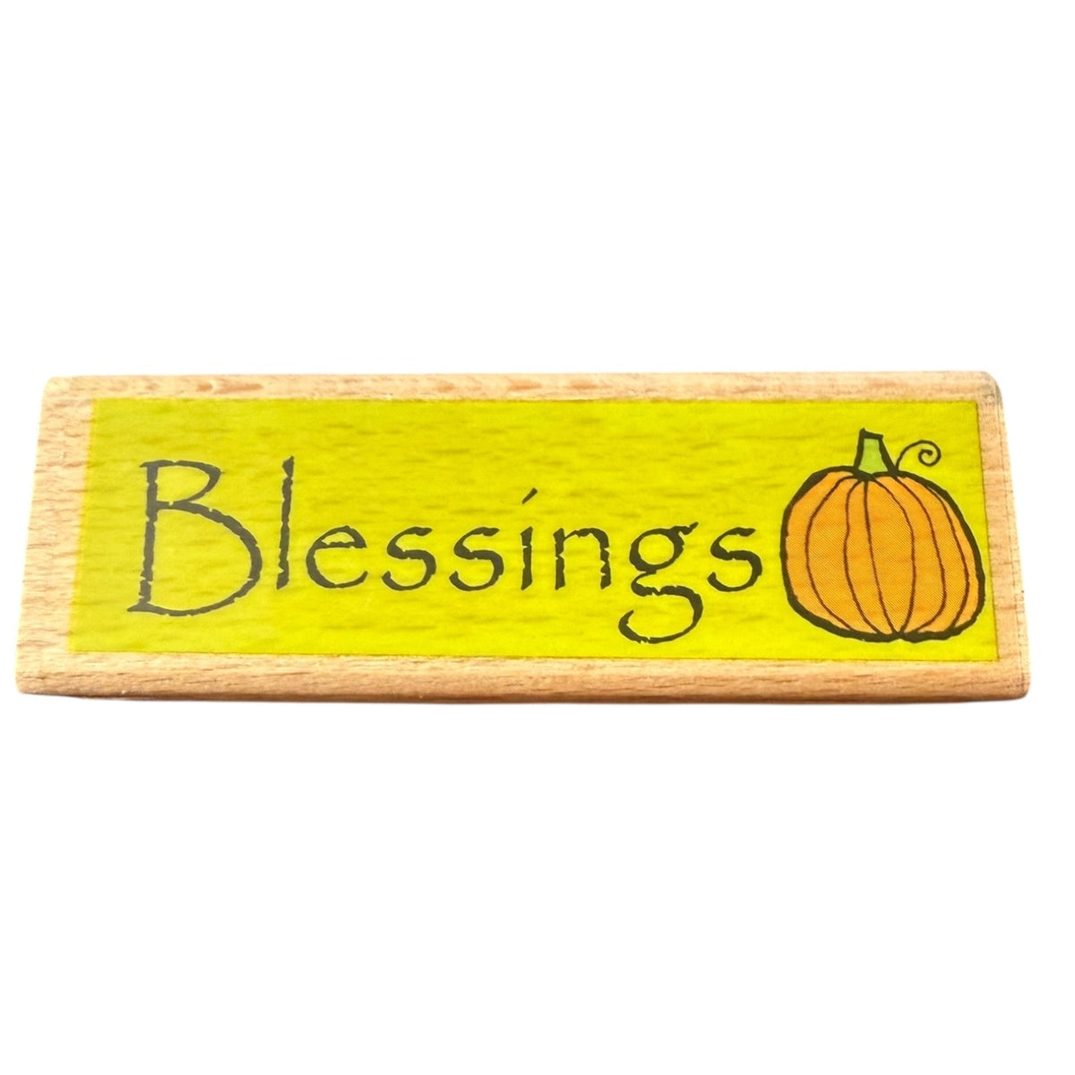 Wooden stamp with 'Blessings' and a pumpkin illustration on a yellow background