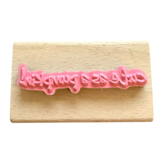 Pink lettering on a wooden block with white background