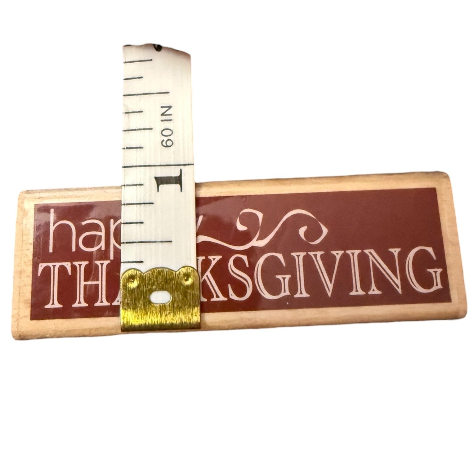 Wood stamp with 'Happy Thanksgiving' text and a measuring tape on a white background