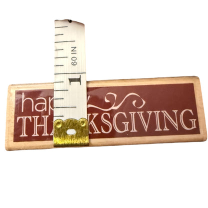 Wood stamp with 'Happy Thanksgiving' text and a measuring tape on a white background