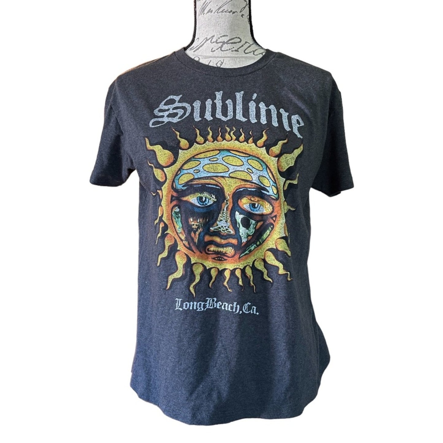 Gray t-shirt with a sun and face graphic and 'Sublime' text on a mannequin against a white background