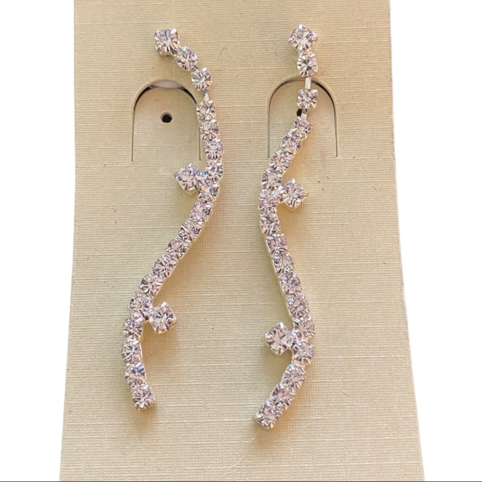 Pair of silver earrings with clear stones on a beige card