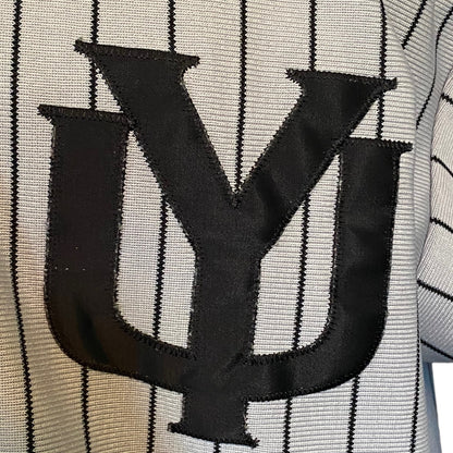 Close-up of a black embroidered stylized 'YU' logo on a gray pinstriped knit fabric.